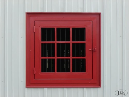 Barn red painted window with black grid muntins on white corrugated metal siding