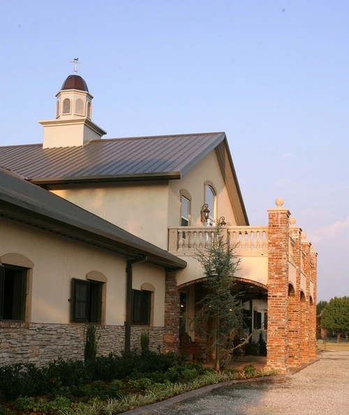 Pale yellow barn exterior with decorative brick trim and arched architectural windows