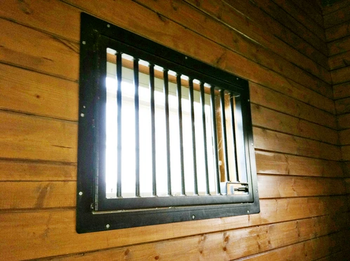 Dark forest green vertical bar window backlit from interior on wood paneled wall