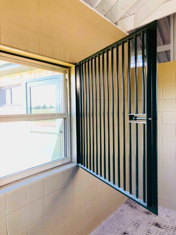 Black vertical bar sliding window panel beside small casement window in bright white interior
