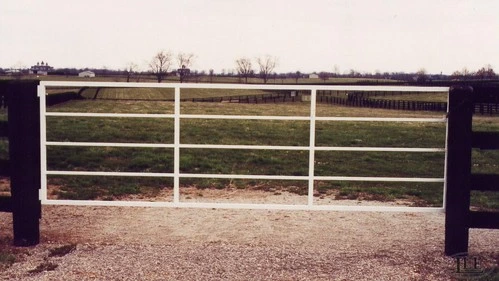 White horizontal pipe rail gate spanning paddock entrance with open field beyond