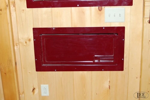 Burgundy painted wooden feed station or tack box with metal water bucket in natural pine barn interior