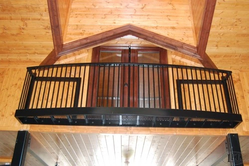 Black metal curved balcony railing with vertical bars under vaulted natural wood plank ceiling