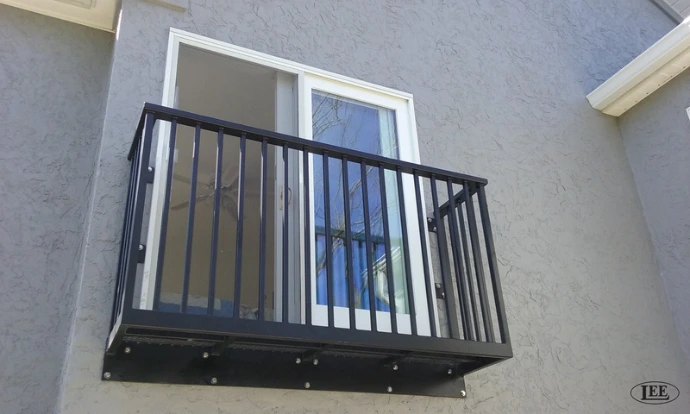 Black metal vertical bar safety railing on small exterior balcony of white painted building