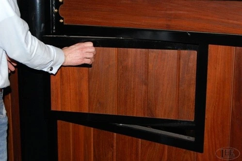 Black metal fold-down tack box or storage cabinet closed showing mahogany wood panel exterior