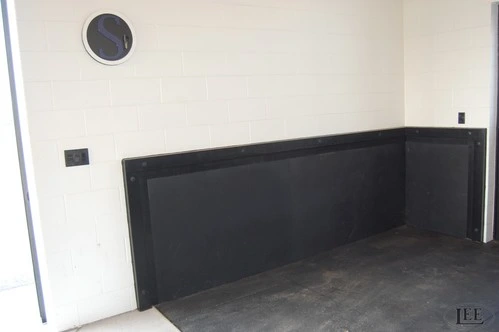 Black metal protective kick panel or lower wall guard mounted on white interior wall