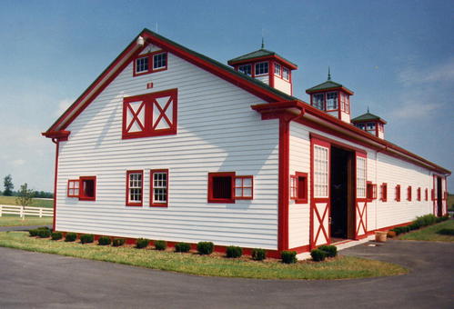 White gambrel barn with red roof, red trim and X-pattern details in rural setting