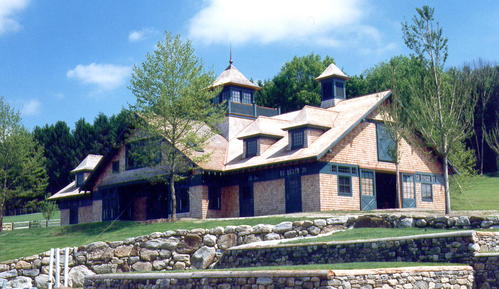 Stone and timber barn with multiple dormers, varied rooflines and rustic retaining walls