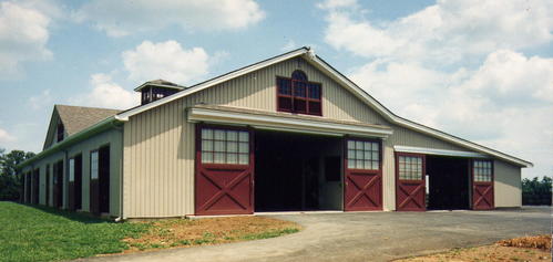 Sage green vertical metal barn with burgundy trim, clerestory windows and skylights