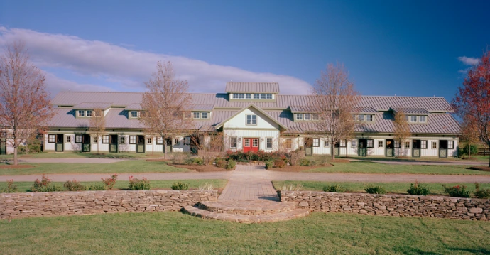Modern commercial barn complex with cream walls and green trim along landscaped campus