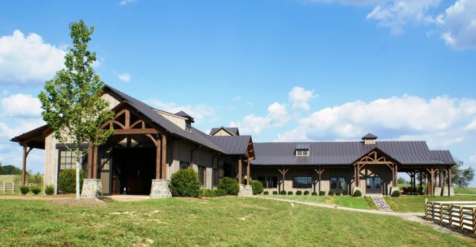 Timber-frame barn with natural wood and white trim, multiple covered openings and cupola