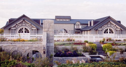 Stone and timber barn complex with multiple levels, arched windows and terraced landscaping with water feature