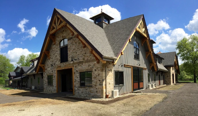 Stone barn with timber-frame details, multiple dormers and covered walkway areas