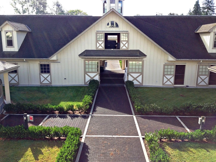 White barn with dark roof, cupola and center breezeway opening viewed from front approach