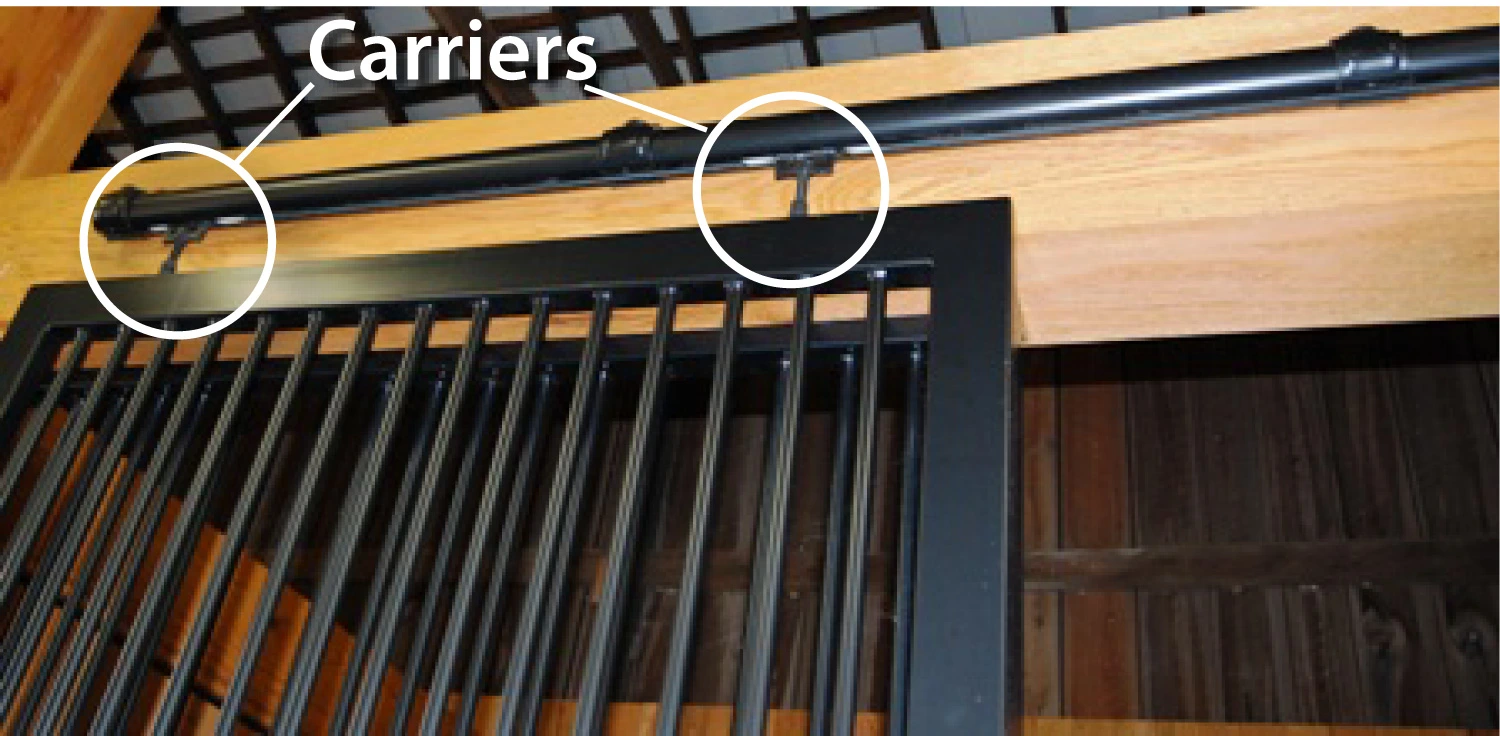 Carriers Detail Image: Close-up of black metal sliding door track with white circles highlighting Delrin wheel carrier components on natural wood header